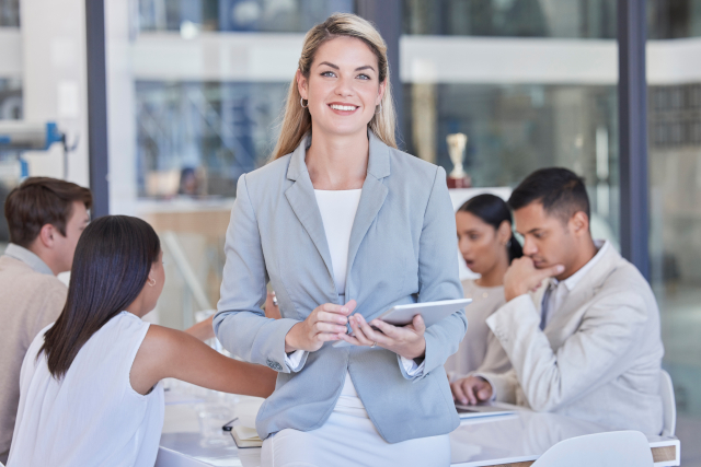 office photo with woman standing in front of staff at a table